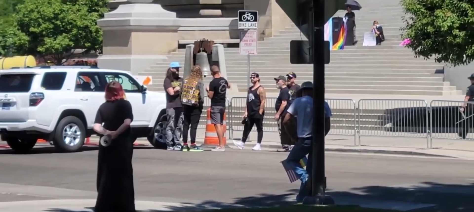 Sean Feucht at the bottom of the Capitol stairs looking on while a queer coded presentation is given by someone who reserved the space before his group of Christian nationalists